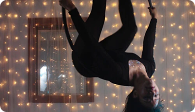 A dancer inverted against a wall of fairy lights