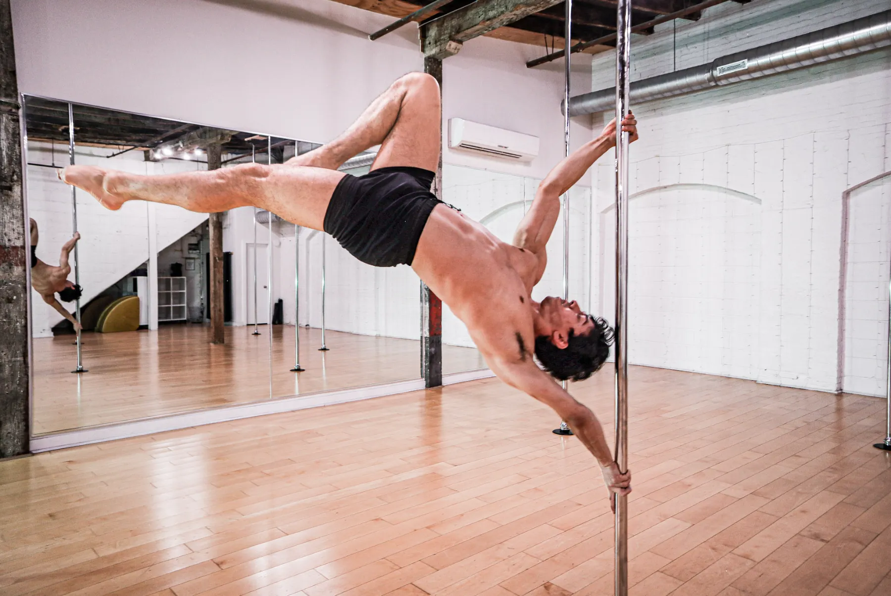 A student extended horizontally on the pole in the Gowanus loft