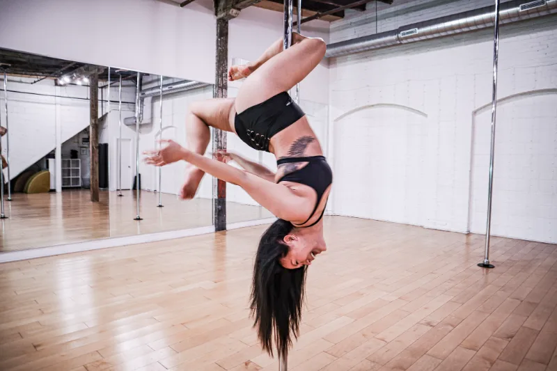 A student holding a pose on the pole in the daylight loft